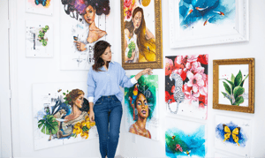 Woman in blue standing in of vibrant colored paintings 